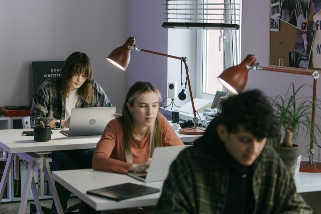 Students working at a shared desk with laptops